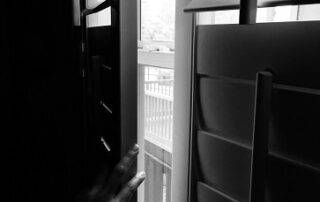 black and white image of hand opening window shutters