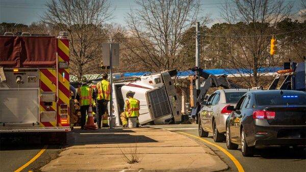 commercial truck tipped over in accident with cars backed up and emrgency vehicle on site